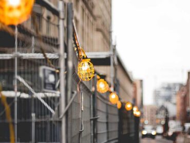 A street light hanging from the side of a fence.