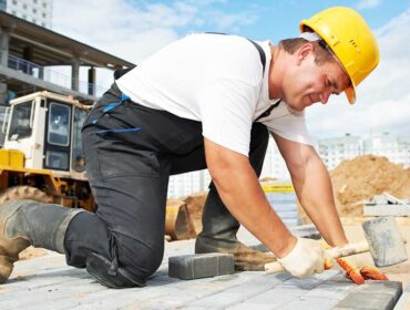 A man in white shirt and black pants holding a hammer.