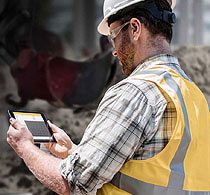 A man in yellow vest holding a tablet.