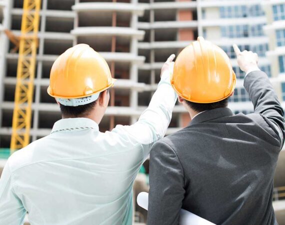 Two men wearing hard hats and one is pointing