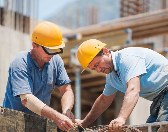 Two men in hard hats working on a building.