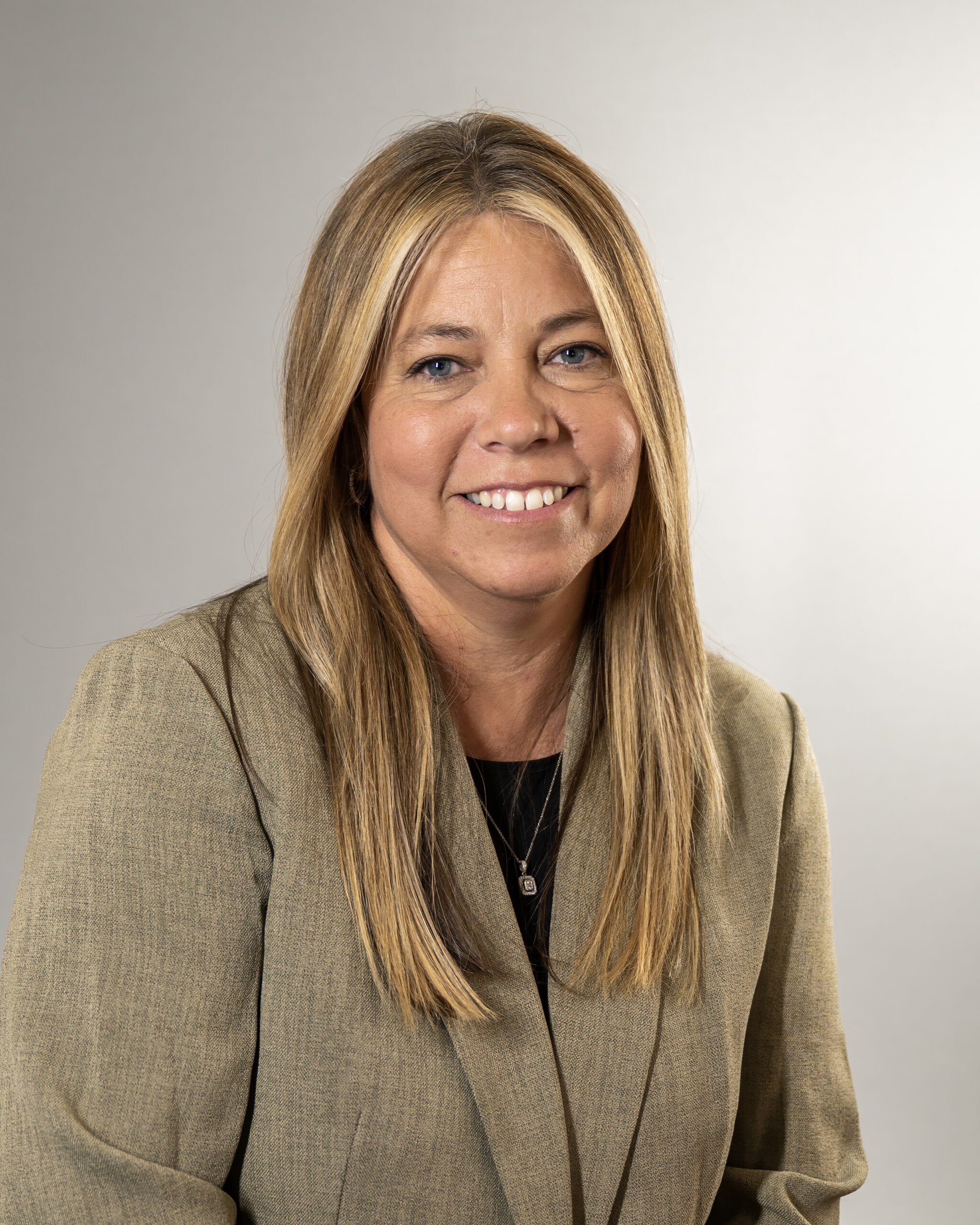 Smiling woman in a beige blazer.