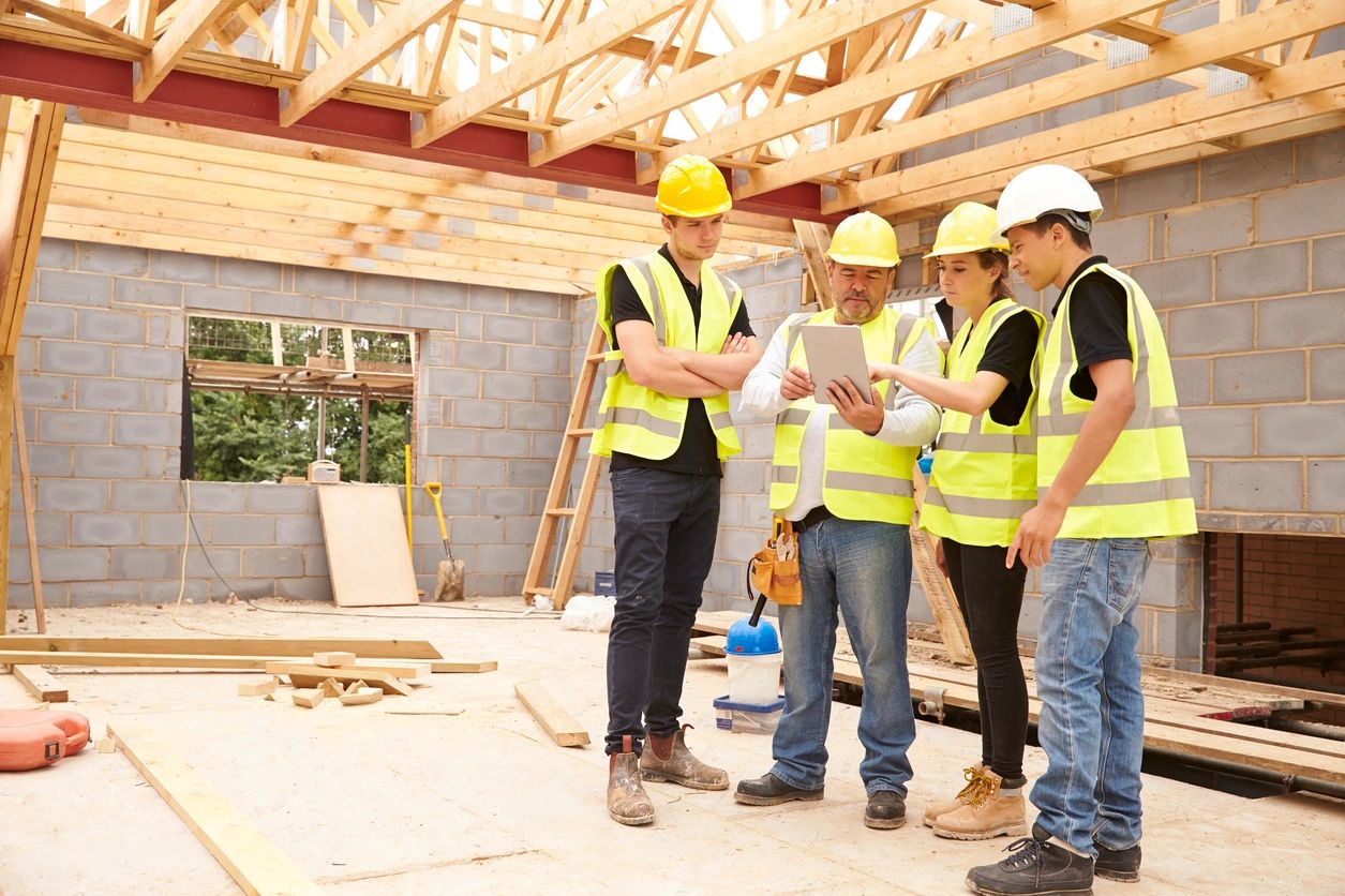 Construction workers reviewing plans on tablet.